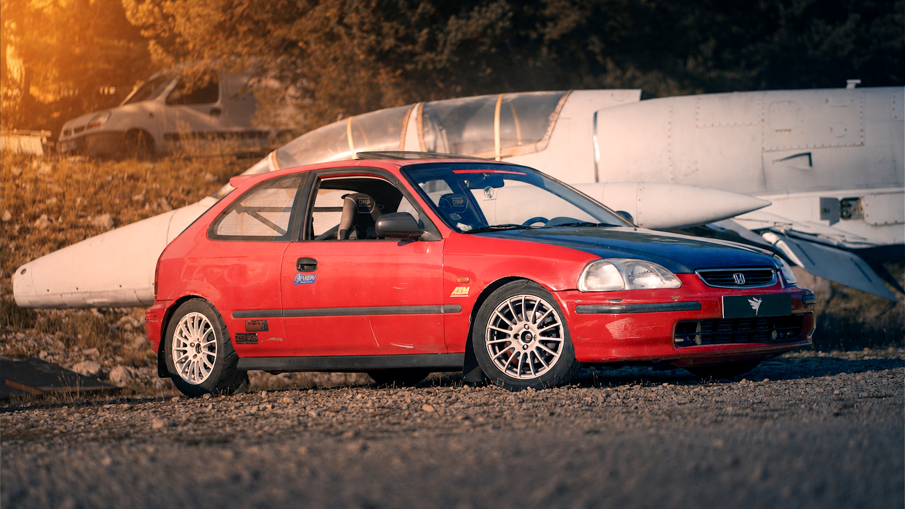 Honda rouge de trois quarts devant un avion
